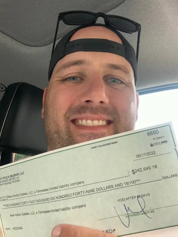Erik in his truck holding the closing check from the flip &mdash; First Volunteer Bank, 06/17/2022, $242,649.18, payable to New Horizon Estates, LLC.